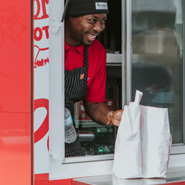 Smiling employee handing food to customer from Beef Bus food truck