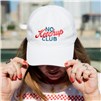 Person wearing a white “No Ketchup Club” cap, holding the brim outdoors.