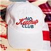 White “No Ketchup Club” cap displayed on a red-and-white picnic-style backdrop.