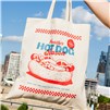 Portillo's Hot Dog Season tote bag held outdoors with city skyline in background