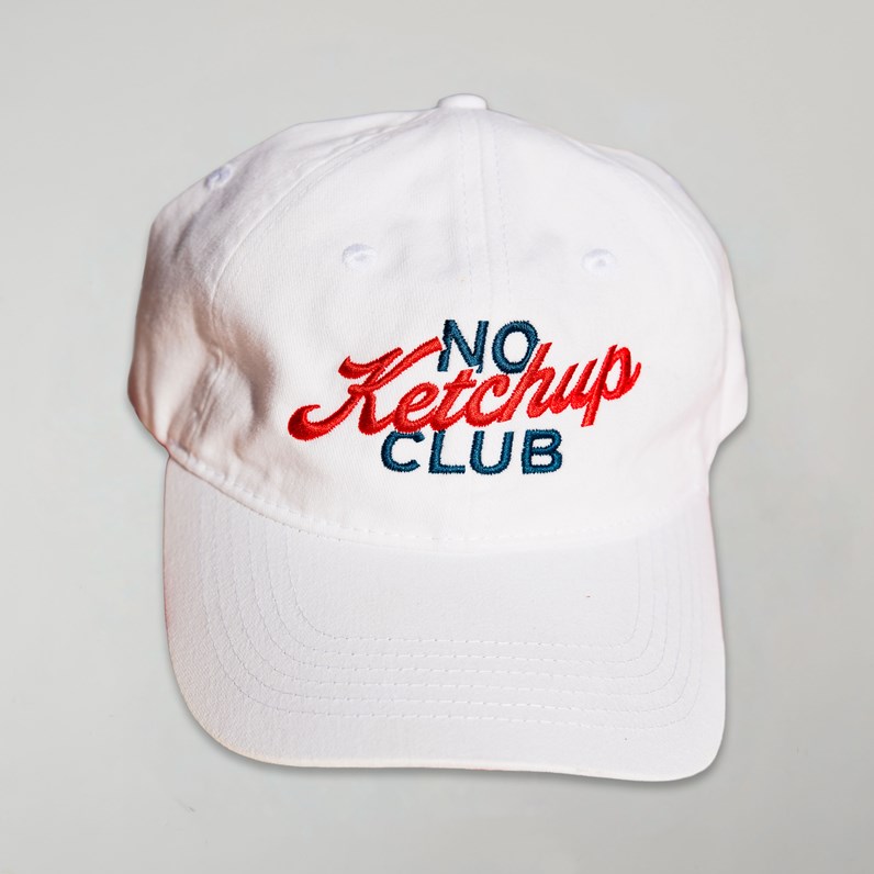 White baseball cap with embroidered &ldquo;No Ketchup Club&rdquo; logo in red and blue.